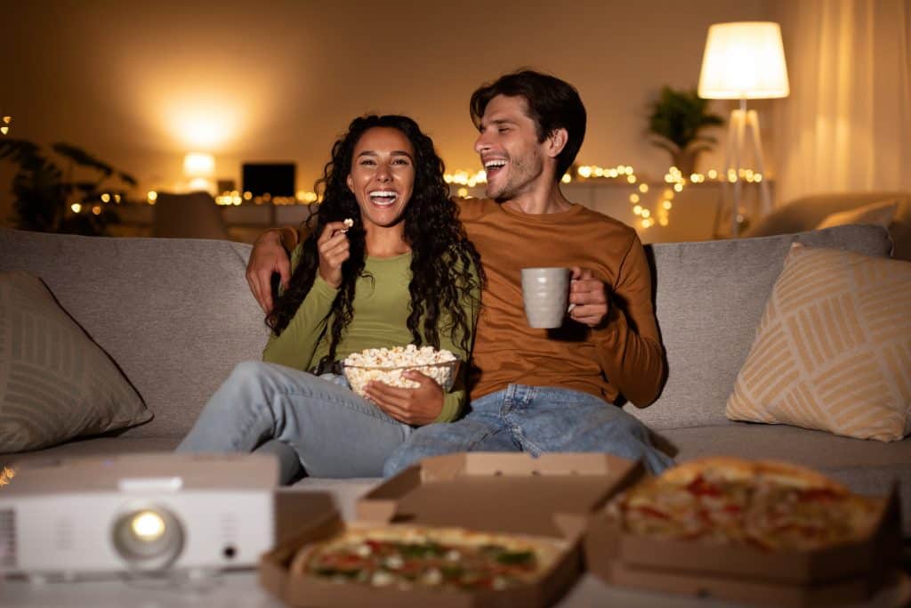 Vrolijk stel kijkt binnen naar een komische film als leuk Date Idee