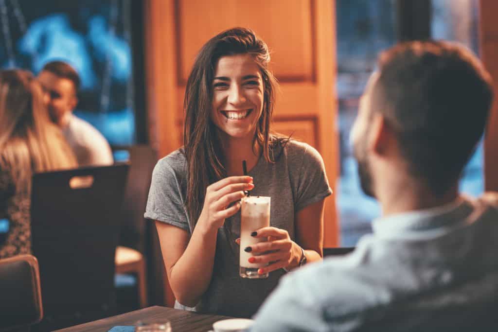 Vrouw lacht om leuke openingszin man in een café