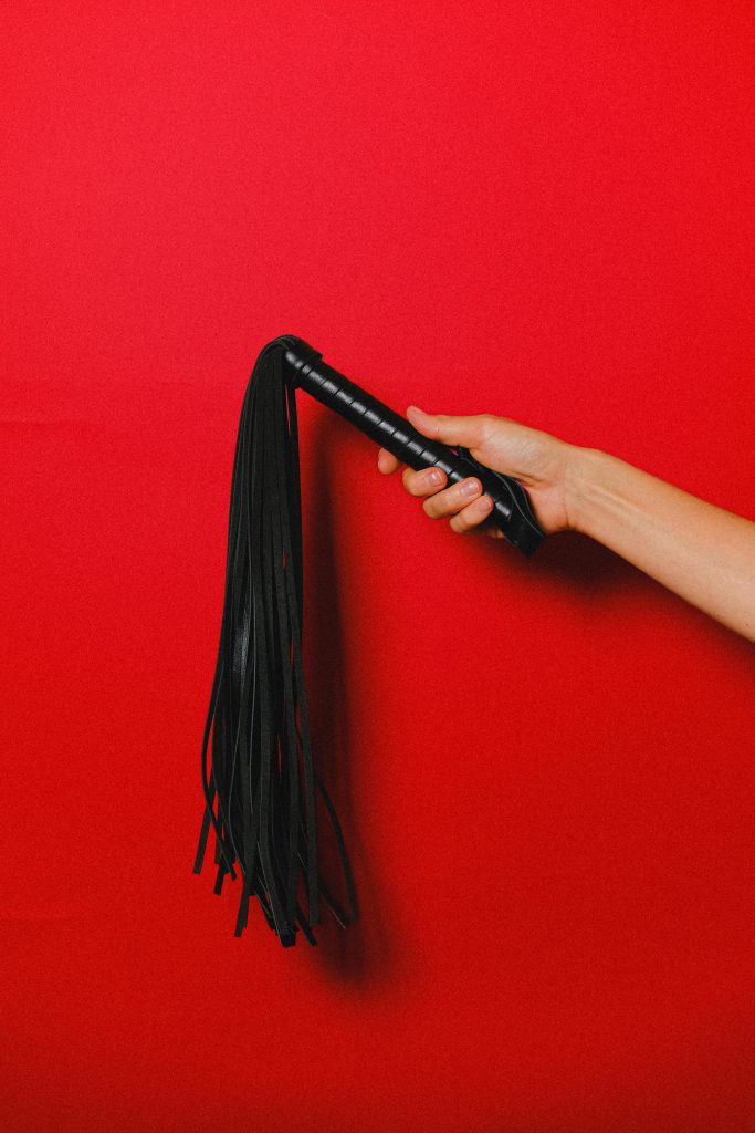 Swingers bondage zweep op rode achtergrond